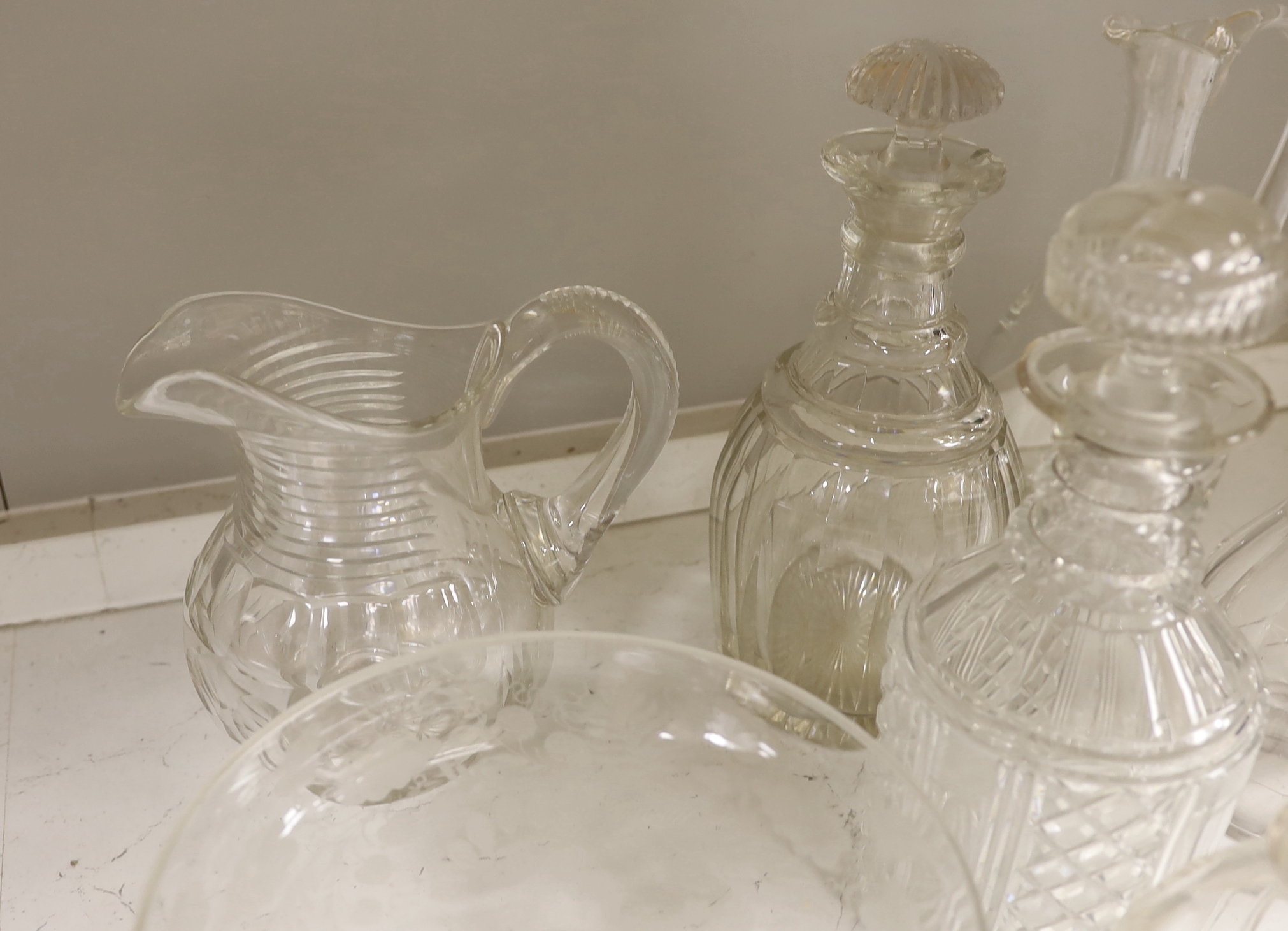 A collection of cut glass decanters and other glassware including five decanters with stoppers, three carafes, two jugs, five shallow round dishes, a pedestal dish, four Crescent dishes and a rinser, tallest 25cm